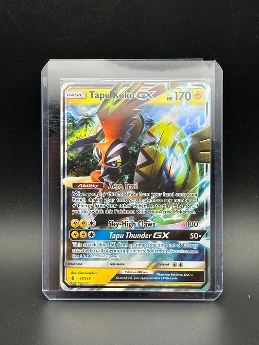 Pokémon trading card featuring Tapu Koko GX on a reflective surface with a dark background